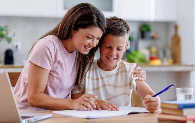 Mother helping a child with homework at a sunlit table